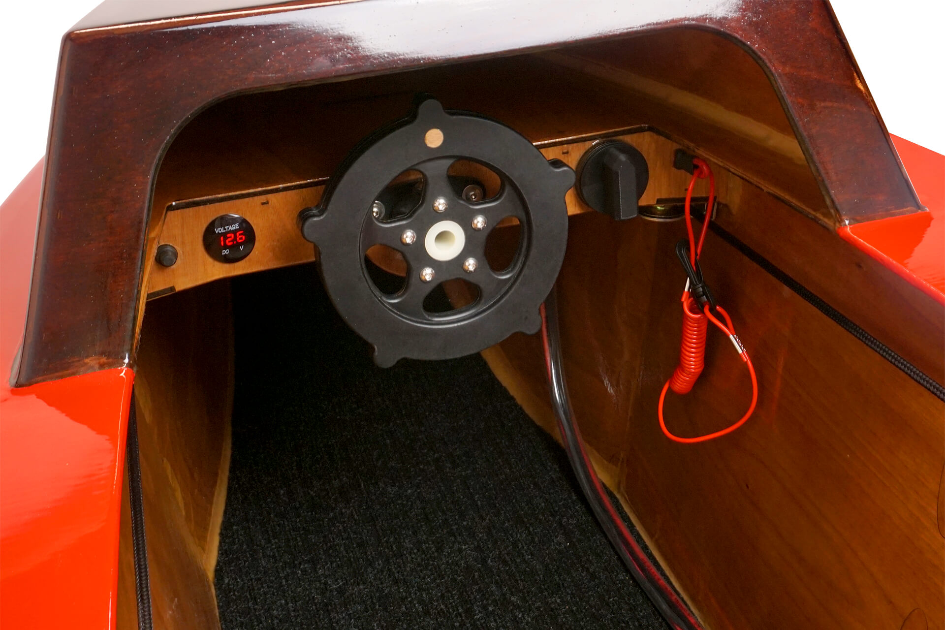 A dashboard view of the mini electric boat, showing off the steering wheel, volt-meter, and dead-mans switch