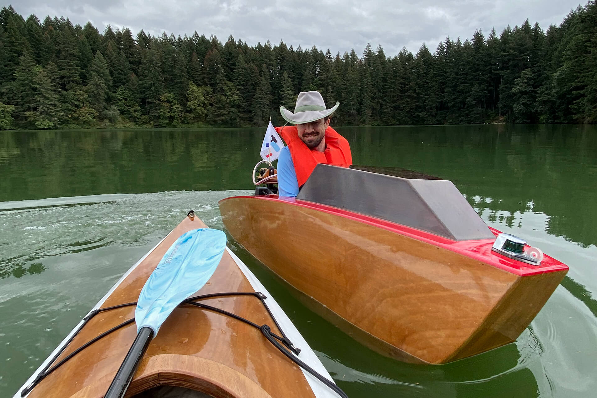 A mini boat gliding by a Chesapeake Light Craft kayak in Round Lake